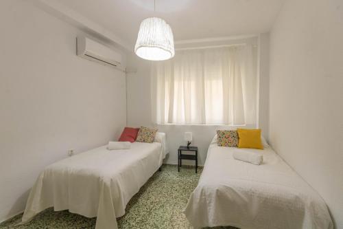 two beds in a white room with a window at Apartamento La Alegria de Córdoba Centro in Córdoba