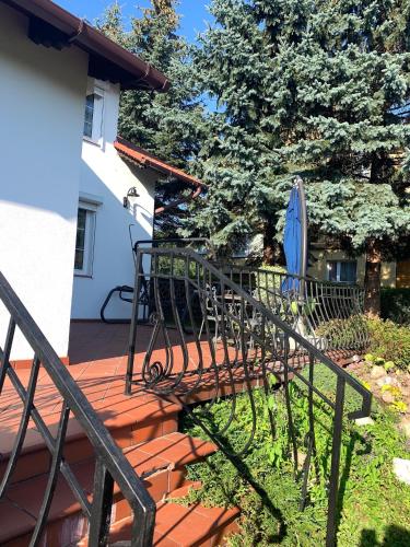 a deck with a chair and umbrella on a house at Willa 250 M z basenem, jacuzzi, ogrodem , tarasem oraz 2 hektary sadu , kominek i inne atrakcje in Buszkowice