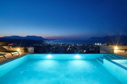a swimming pool with a view of the city at night at Luxury Villa Argi infinity private pool in Kissamos