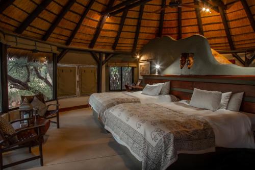 a bedroom with two beds in a room with windows at Okonjima Luxury Bush Camp in Otjiwarongo