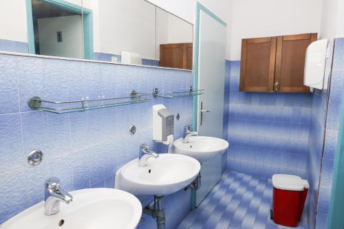 un bagno piastrellato blu con due lavandini e uno specchio di HI Hostel Dubrovnik a Dubrovnik