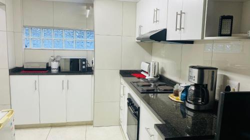 a kitchen with white cabinets and a black counter top at La Lucia Sleepover in Durban