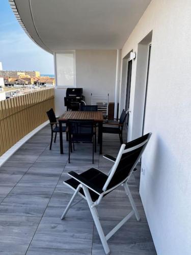 a patio with a table and chairs on a balcony at T2 neuf + piscine, 5 mn à pied des plages in Sérignan