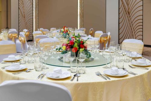 a table with glasses and a vase of flowers on it at Wyndham Garden Cam Ranh Resort in Cam Ranh