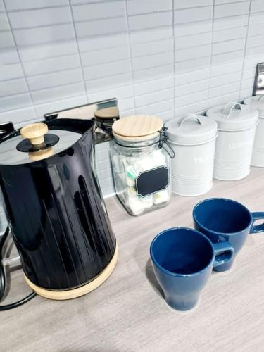 a coffee pot and some blue cups on a counter at Spacious 5bed house, FREE parking, NO PARTY ! in Glasgow