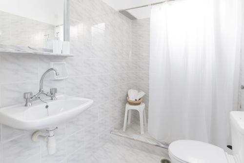 a white bathroom with a sink and a toilet at Emerald Hotel Leros in Alinda