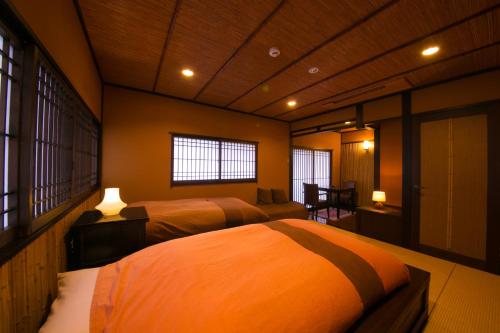 a bedroom with two beds and two windows at Bettei Haruki in Beppu