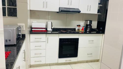 a kitchen with white cabinets and a counter top at La Lucia Sleepover in Durban