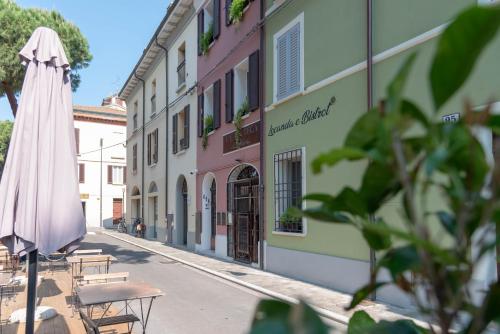 a pink building with a umbrella and tables on a street at Le camere di Olivia in Ravenna