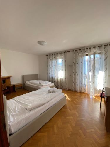 two beds in a room with wooden floors and windows at Casa Ahmati Borgo Vesio in Tremosine Sul Garda