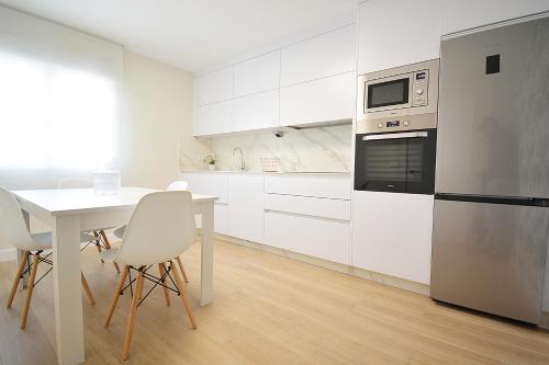 uma cozinha branca com uma mesa e um micro-ondas em Apartamento Aires de Lavanda em Sanxenxo
