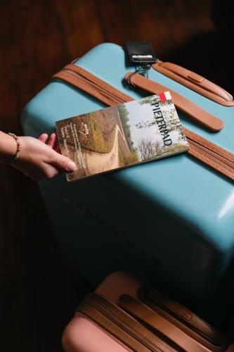 a person holding a book next to a suitcase at Villa-Hotel De Kroon Gennep in Gennep