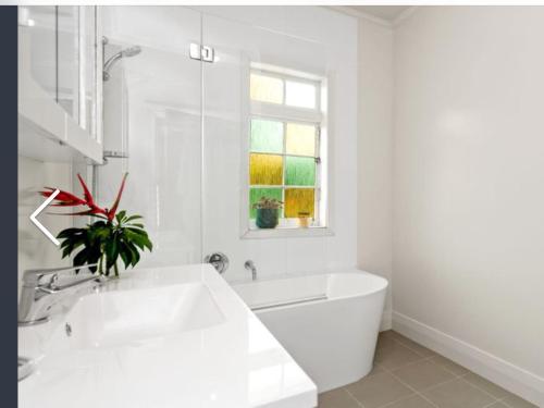 a white bathroom with a white tub and a window at Northern Holiday Cottage in Whangarei
