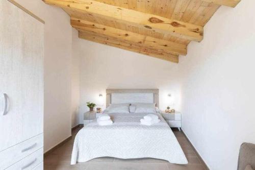 a bedroom with a large white bed with a wooden ceiling at Apartamentos El Mirador in Villarroya de los Pinares