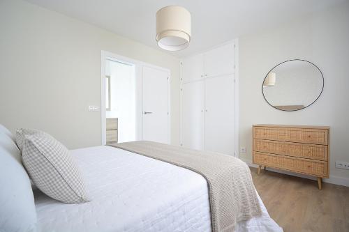 um quarto branco com uma cama e um espelho em Apartamento Aires de Lavanda em Sanxenxo