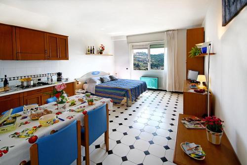 een keuken en een woonkamer met een tafel en een bed bij Residence Hotel Edy in Imperia