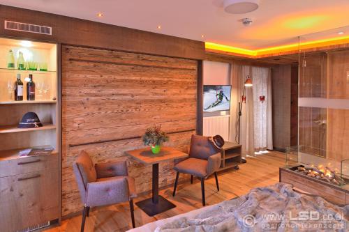 - un salon avec un mur en bois, une table et des chaises dans l'établissement Berghotel Pointenhof, à St. Johann in Tirol