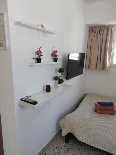 Dieses weiße Zimmer verfügt über einen Tisch, ein Bett und einen TV. in der Unterkunft Explore Greece from Cozy City Centre Apartment in Chalkida