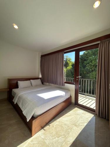 a bedroom with a bed and a balcony with a window at EL Suites Berawa - Canggu in Canggu