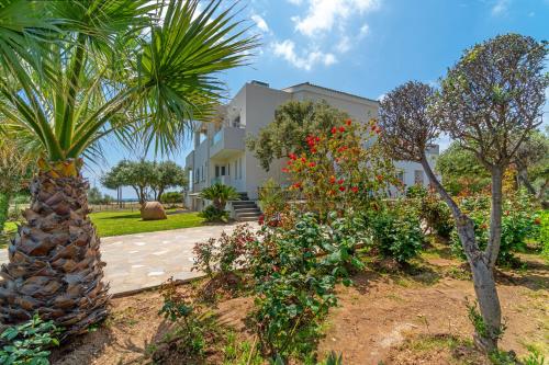 a house with a palm tree and flowers in a yard at Legrena Beach House in Sounio