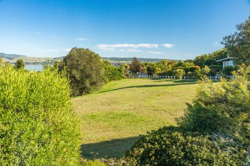 a field of grass with trees and a house in the background at Tranquil Retreat in Taupo