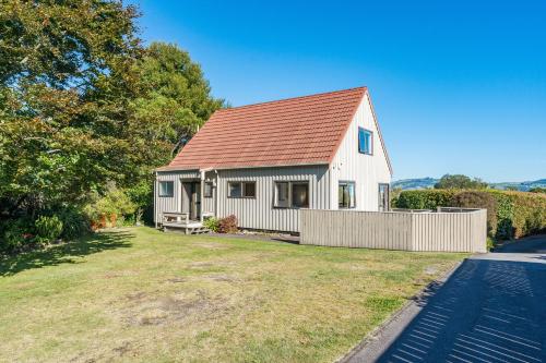 a white house with a red roof on a yard at Tranquil Retreat in Taupo