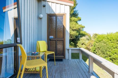 a porch with two yellow chairs and a table at Tranquil Retreat in Taupo