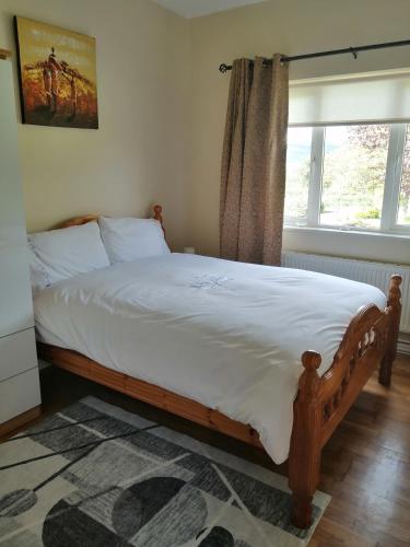 a bedroom with a large bed with white sheets and a window at An Cúinín in New Ross