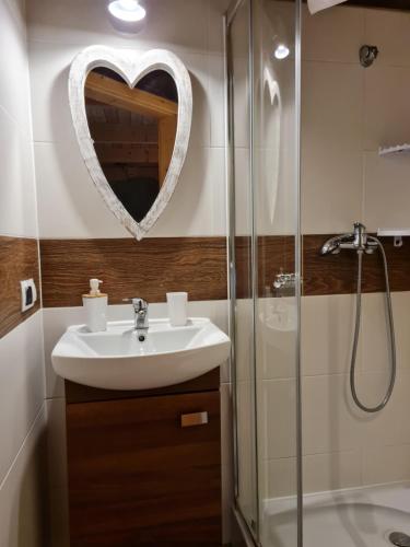 a bathroom with a sink and a heart mirror at Chata w Rabce - Bajkowa Osada in Rabka