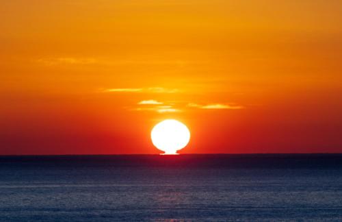a sunset over the ocean with the sun in the sky at Hotel Maremons in Sokcho