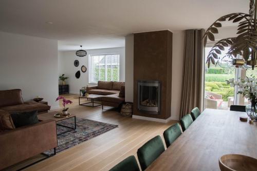 a living room with a table and a fireplace at Villa Rust-en-Vrede met hottub in Zeewolde