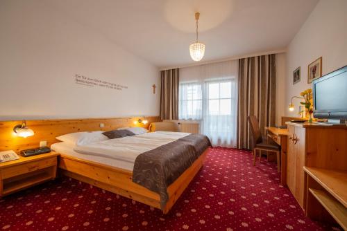 Sankt Oswald的住宿－古拉克斯蘭德費舍爾酒店，配有一张床和一台平面电视的酒店客房