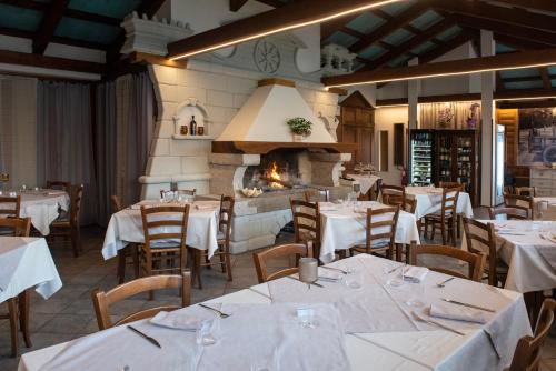 un restaurante con mesas y sillas blancas y chimenea en Albergo Alla Cesa, en Feltre