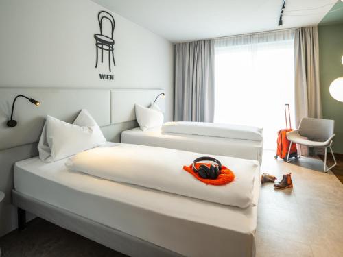 a hotel room with two beds and a chair at ibis Styles Graz Messe in Graz