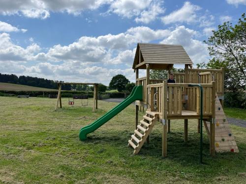 a wooden playground with a slide and a slideintend at Dukeries Retreat in Retford