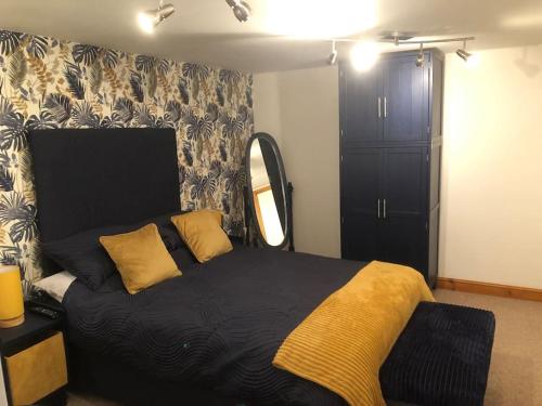1 dormitorio con cama negra y almohadas amarillas en Adorable 1 bedroom apartment in Ironbridge en Telford