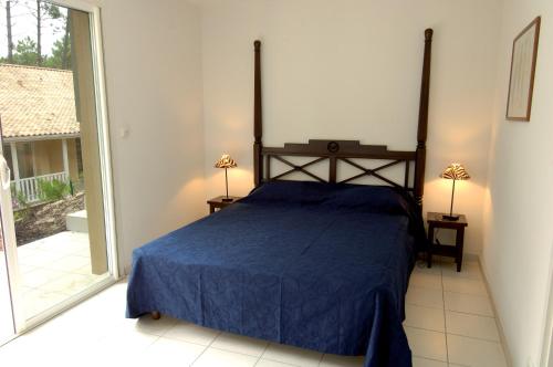 sypialnia z łóżkiem z niebieską narzutą w obiekcie Lagrange Vacances - Eden Parc Golf w mieście Lacanau-Océan