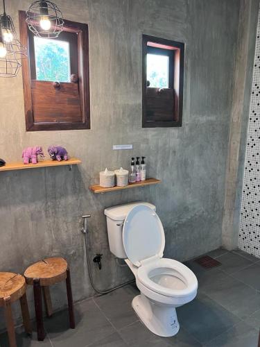 a bathroom with a toilet and two tables and a window at Moonlight Champa Riverview in Luang Prabang