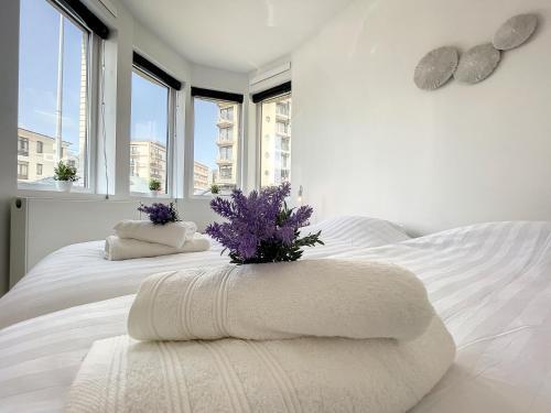 a white bed with white blankets and purple flowers on it at Villa SeaShell - Luxurious renovated gas station in Koksijde