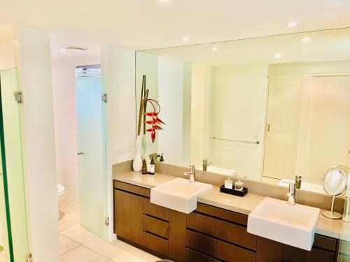 een badkamer met 2 wastafels en een grote spiegel bij Tropical Retreat - Poolside Swimout - Ground Floor - Sea Temple Resort & Spa Port Douglas in Port Douglas