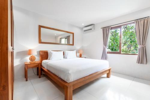 a white bedroom with a bed and a mirror at Du Ciel Villa by Hombali in Canggu