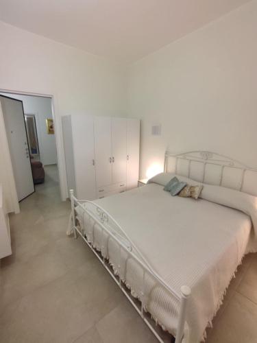 Cette chambre comprend un grand lit blanc et des armoires blanches. dans l'établissement Le Casette di Adele, à Palagiano