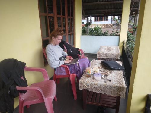 een vrouw in een stoel naast een tafel bij Mushtinal Guest House in Ende