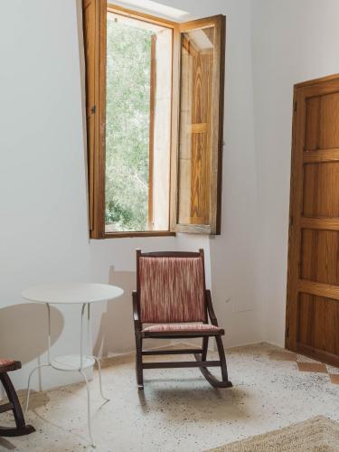 a chair sitting in a room with a table and a window at Llucamar Villa in Sant Llorenç des Cardassar