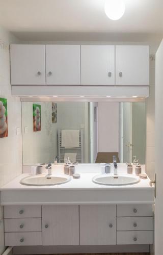 une salle de bain avec deux lavabos et un grand miroir dans l'établissement Appartement en résidence Le Mans, au Mans