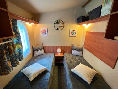 a room with two beds and a table and a window at Bungalow de 2 chambres avec piscine partagee jardin clos et wifi a Saint Jean de Valeriscle in Saint-Jean-de-Valériscle