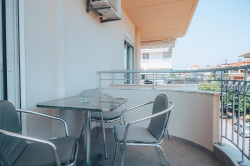 a balcony with a glass table and chairs on it at Dionysos Rooms in Olympiaki Akti