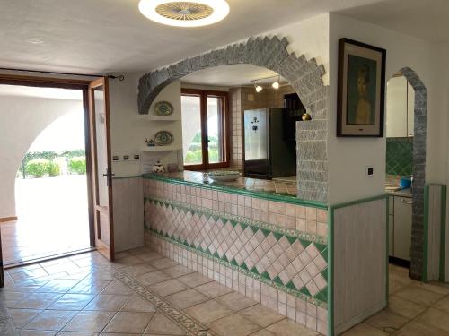 une cuisine avec un comptoir en carrelage et une arche dans l'établissement Appartamento in villa panoramica Maladroxia, à Maladroscia
