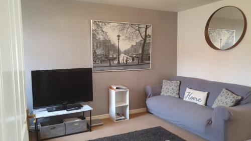 uma sala de estar com um sofá azul e uma televisão de ecrã plano em Larkspur House in West midlands em Bedworth