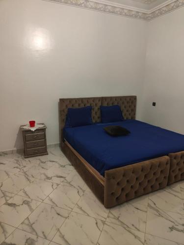 a bedroom with a bed with blue sheets and a table at STUDIO NEUF PROPRETE ET HYGIENE IRREPROCHABLE Proche des bus CTM - 4 em étage face terrasse in Tangier